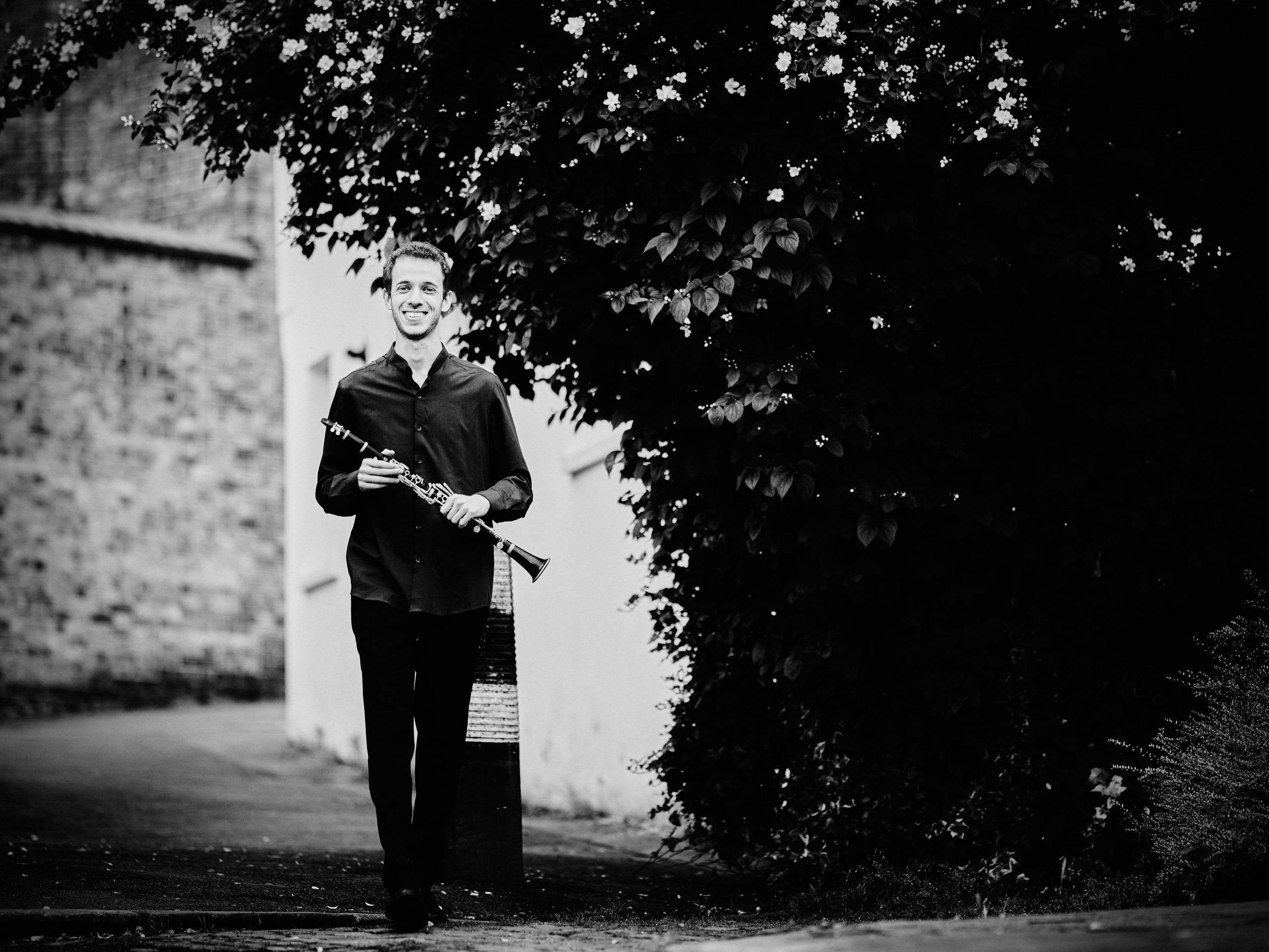 Black-and-white photograph of Jonathan Leibovitz walking out of a leafy garden
