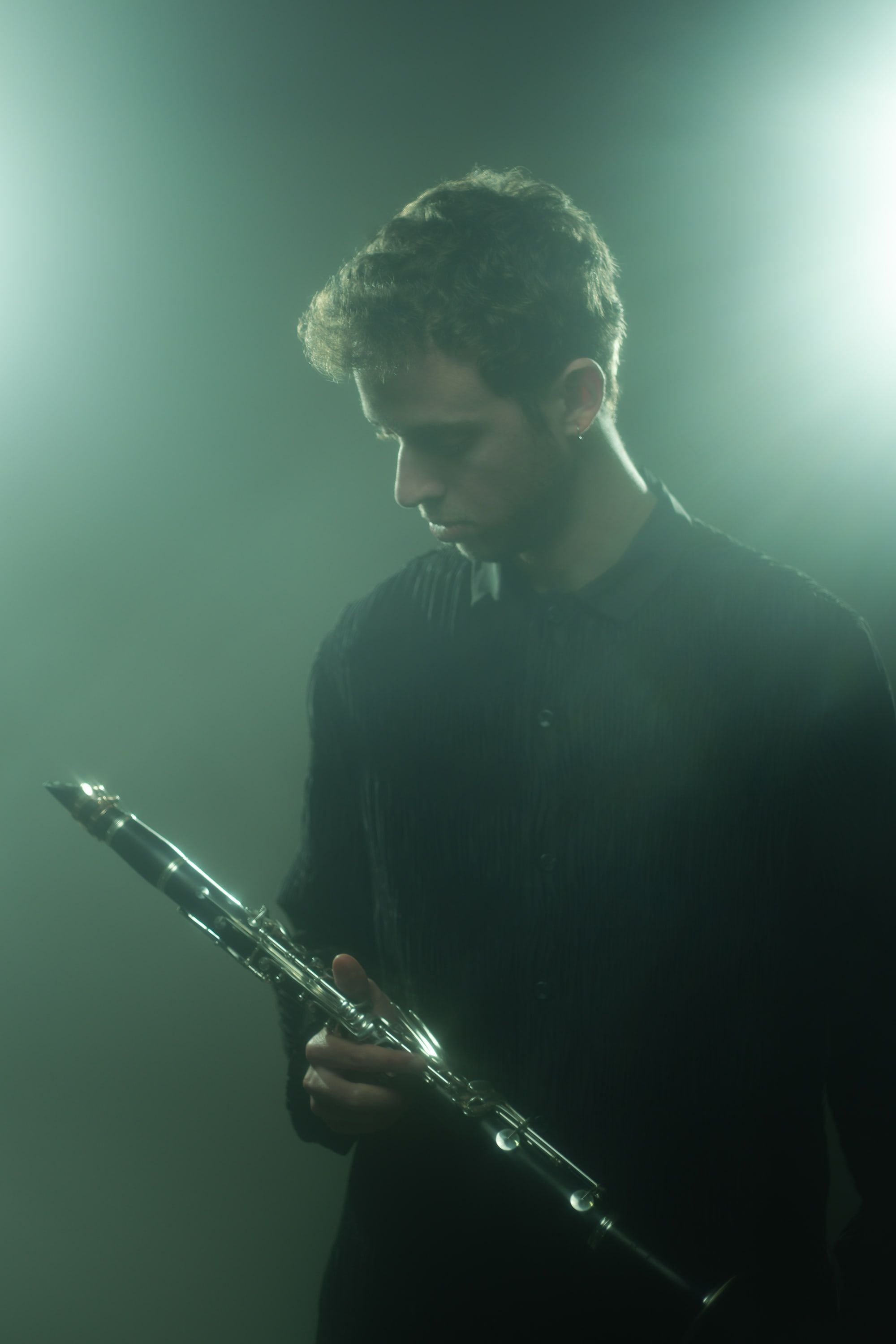 Jonathan Leibovitz in teal haze, looking down at his clarinet