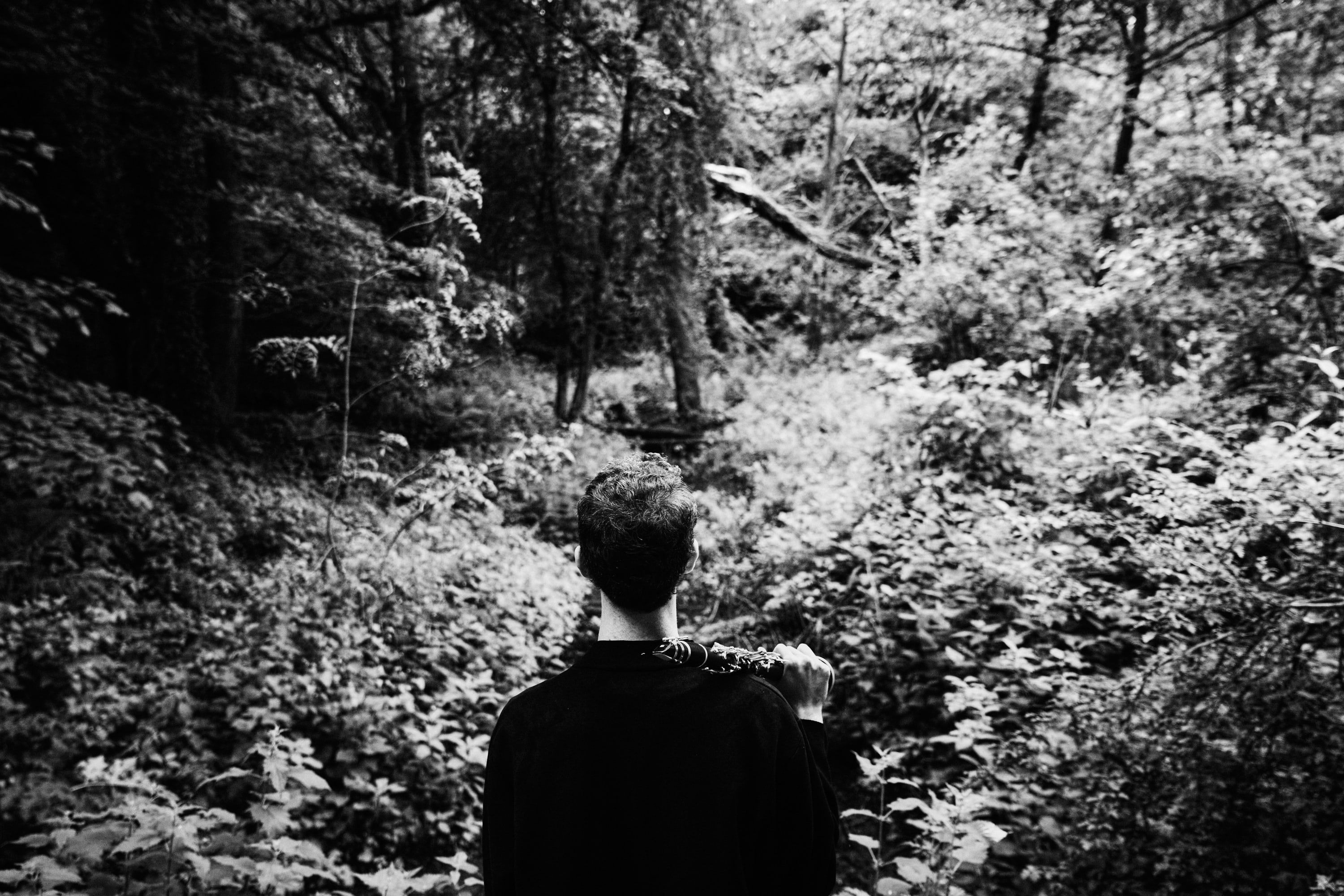 Black-and-white photograph of Jonathan Leibovitz seen from behind in dense woodland