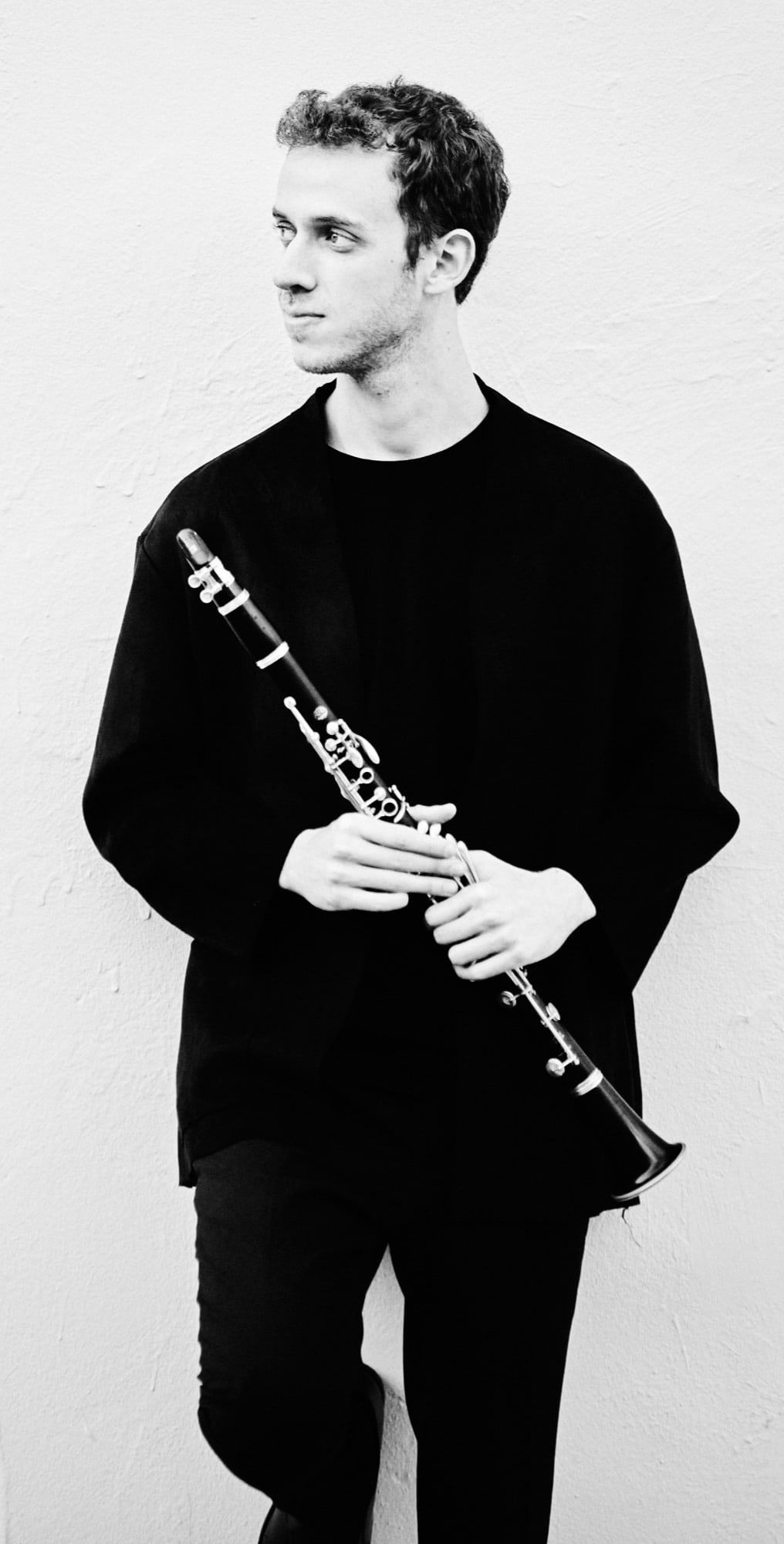 Black-and-white photograph of Jonathan Leibovitz against a white wall, clarinet in hand
