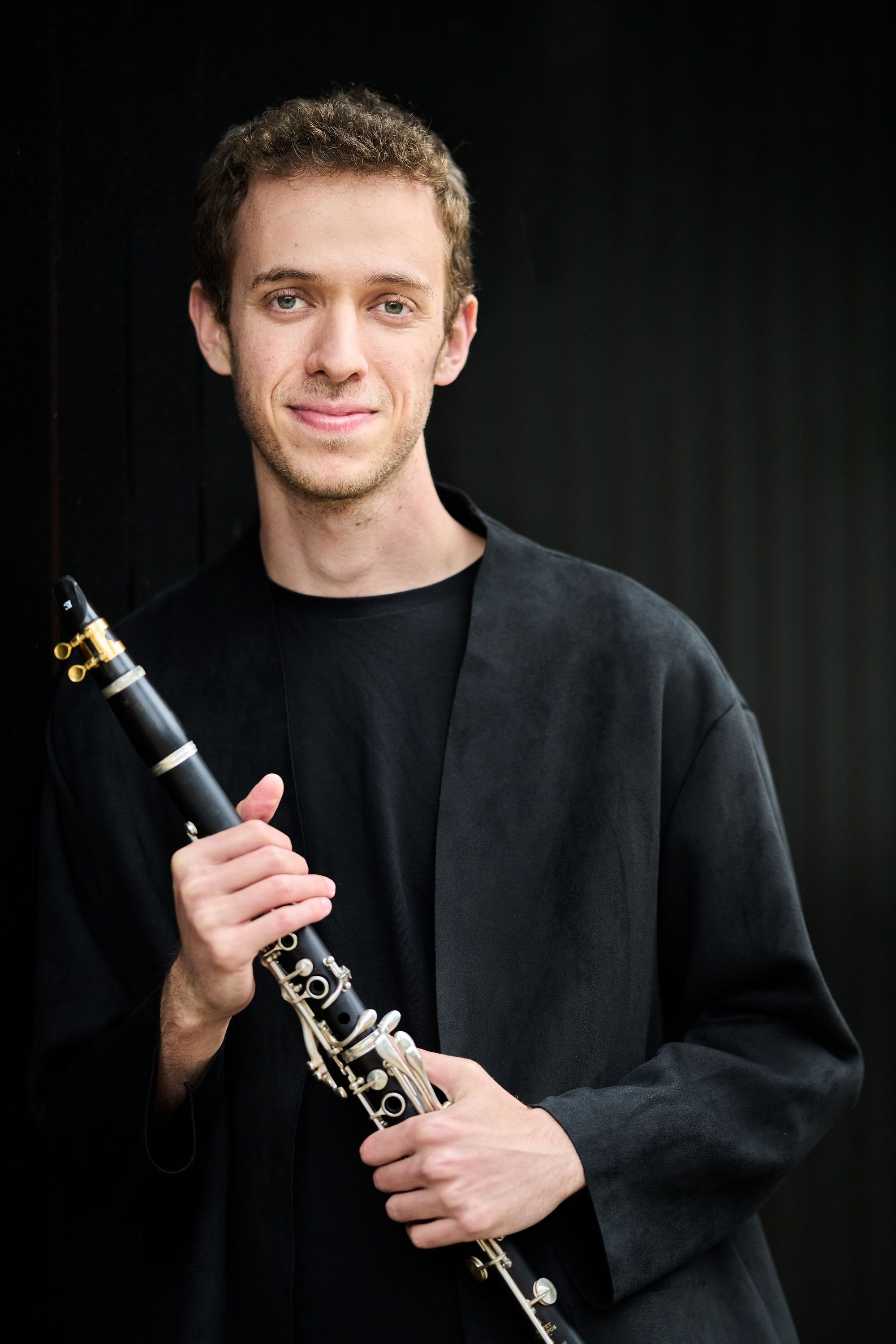 Jonathan Leibovitz in a black jacket, smiling, clarinet in hand
